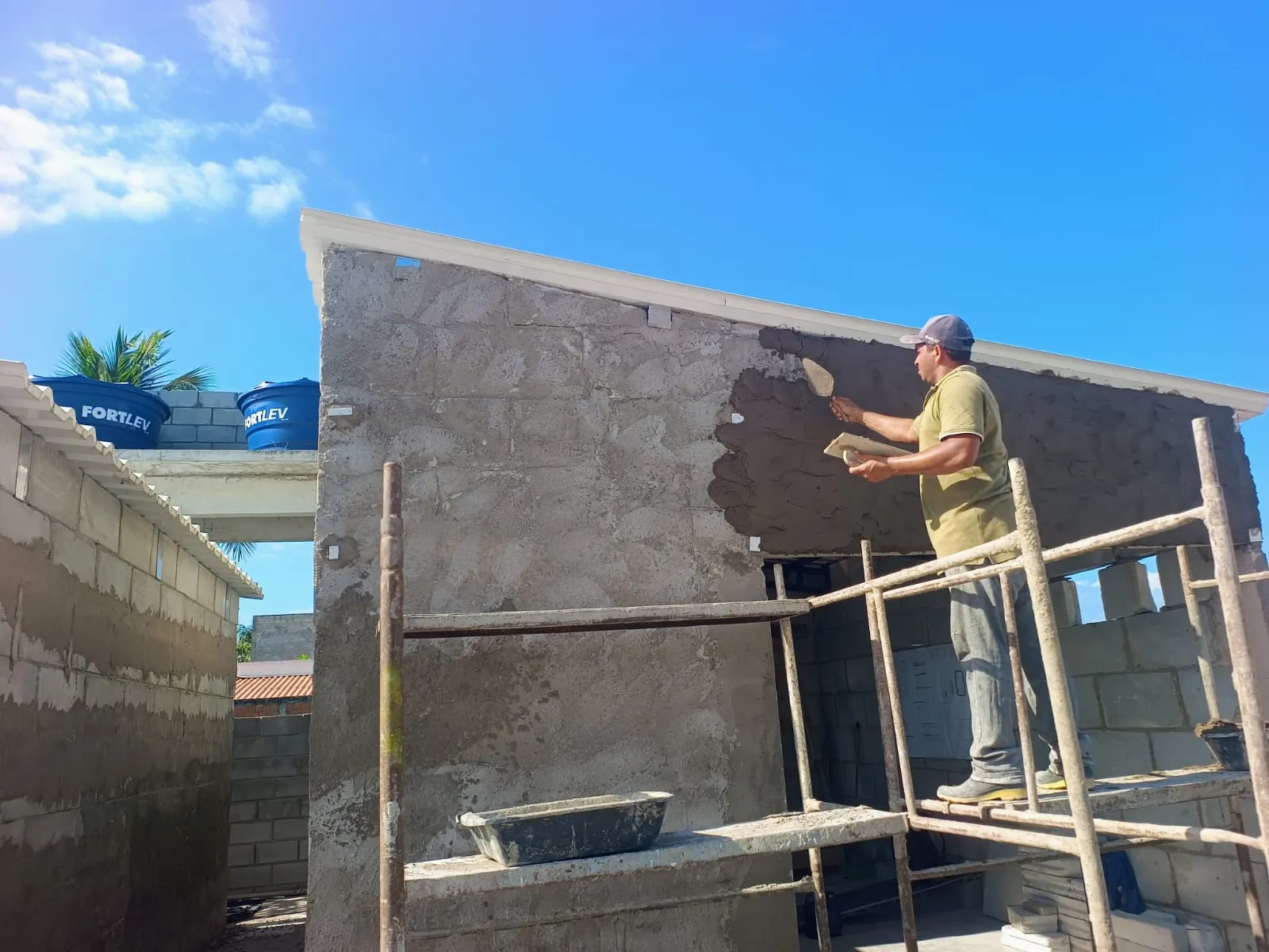 Pedreiro aplicando reboco na parede de um estúdio