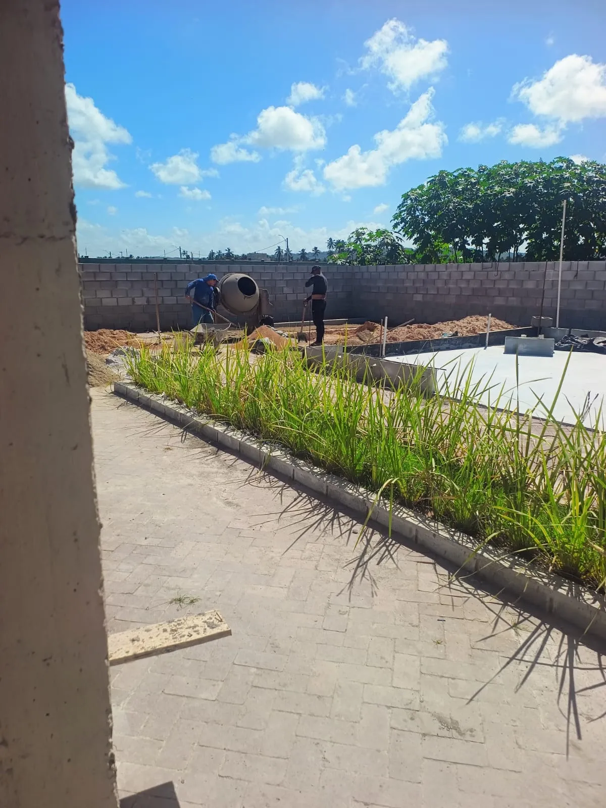 Área da obra com canteiro de grama e muro de divisa